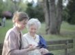 Life insurance claims - a young woman with an older woman sitting on a park bench.
