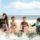 Travel insurance coverage - four happy children in wetsuits splashing in the sea