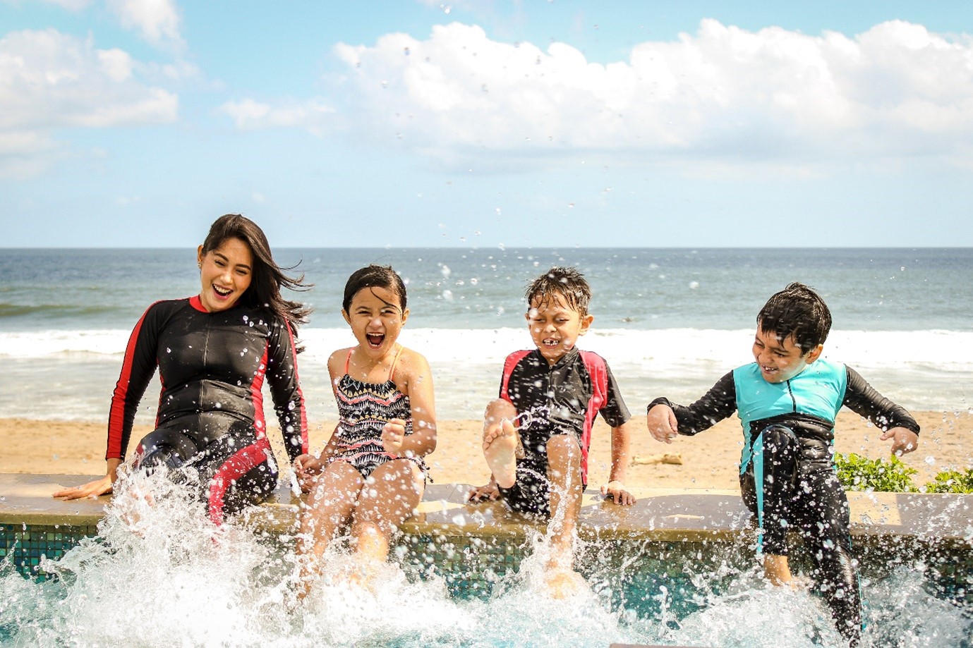 Picture1 Travel insurance coverage - four happy children in wetsuits splashing in the sea